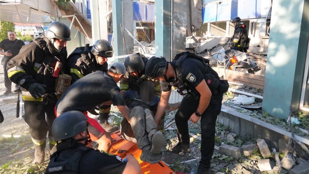 Рятувальники та поліціянти допомагають постраждалому після обстрілу автовокзалу Запоріжжя