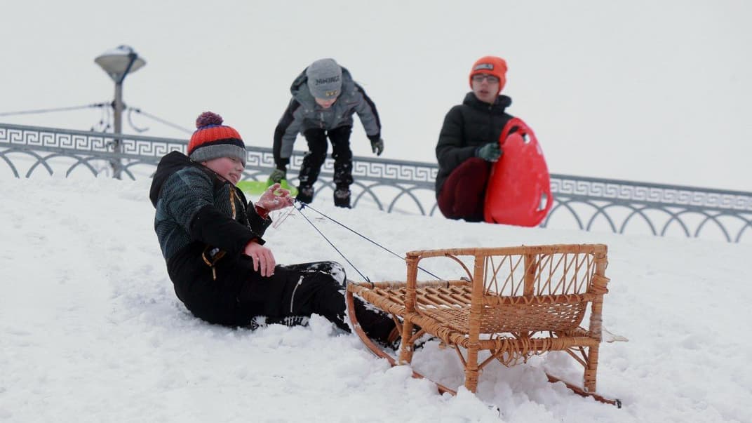 Хлопчик піднімається на снігову гірку із санчатами у Києві, 1 грудня 2023 року