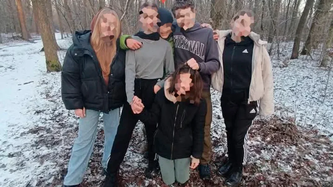 Фігуранти справи позують біля постраждалої, яка стоїть на колінах