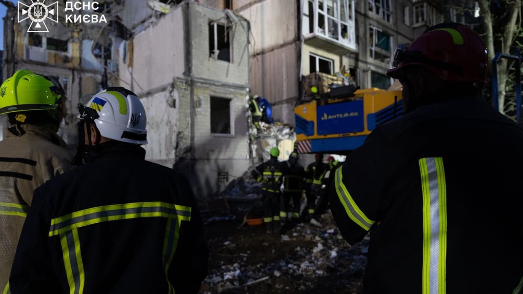 Спасатели работают на месте попадания российской ракеты в Святошинском районе Киева