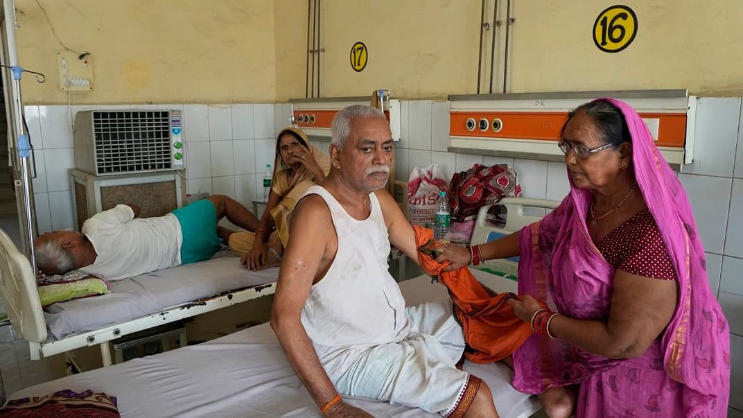 Женщина обтирает руку своего больного брата влажной тканью, чтобы помочь пережить экстремальную жару, Баллия, Уттар-Прадеш, Индия, 19 июня 2023 года