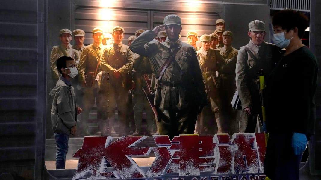  Люди проходят мимо афиш фильма о корейской войне «Битва на озере Чанджин» в кинотеатре в Пекине, Китай, 1 октября 2021 года