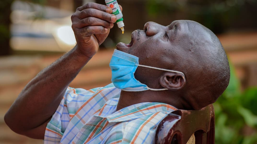 Чоловік з кашлем, але не пройшов тестування на коронавірус, використовує COVIDEX, місцевий рослинний препарат, схвалений урядом для використання як допоміжний засіб лікування вірусних інфекцій, у Кампалі, Уганда, 6 липня 2021 року.
