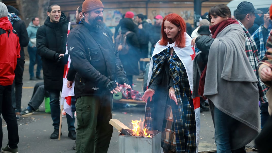 Протестующие греются у костра во время митинга против результатов парламентских выборов, Тбилиси, Грузия, 18 ноября 2024 года