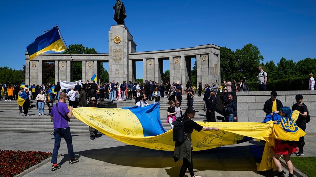 Люди розгортають прапор України біля радянського військового меморіалу в Тіргартені, Берлін, 8 травня 2022 року