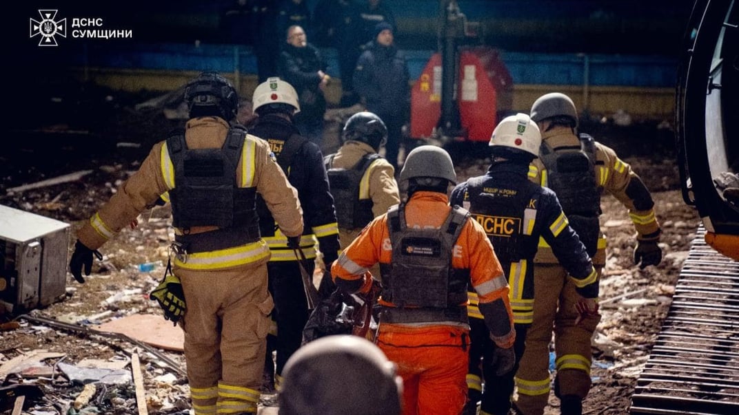Рятувальники несуть тіло загиблої людини на місці влучання російського дрона в Сумах