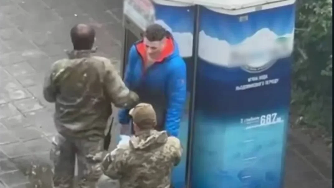Військові Харківського ТЦК перевіряють документи в чоловіка, якого згодом вдарили