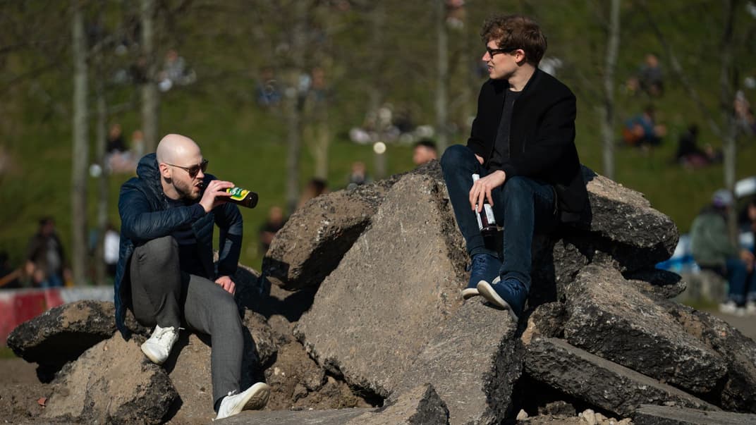 Двое мужчин пьют пиво в парке в воскресный день в Берлине, Германия, 5 апреля 2020 года