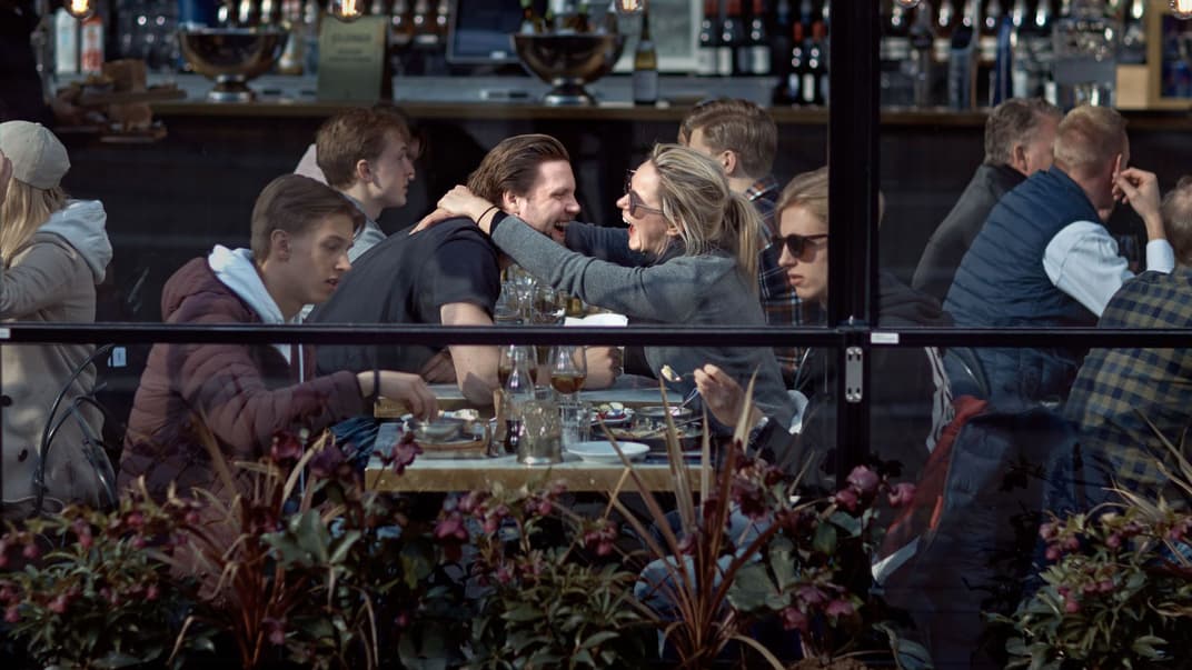 Пара обнимается и смеется, обедая в ресторане в Стокгольме, Швеция