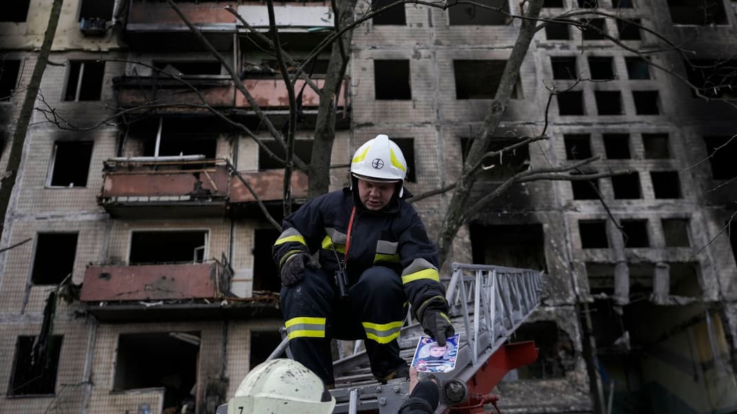 Українські вогнеборці тримають фотографію, знайдену під завалами житлового будинку після артилерійського обстрілу, Київ, 14 березня 2022 року