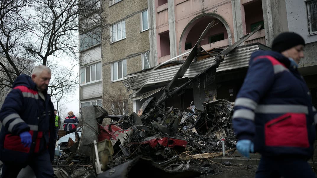 Робітники проходять повз місце падіння вертольота у Броварах, 18 січня 2023 року