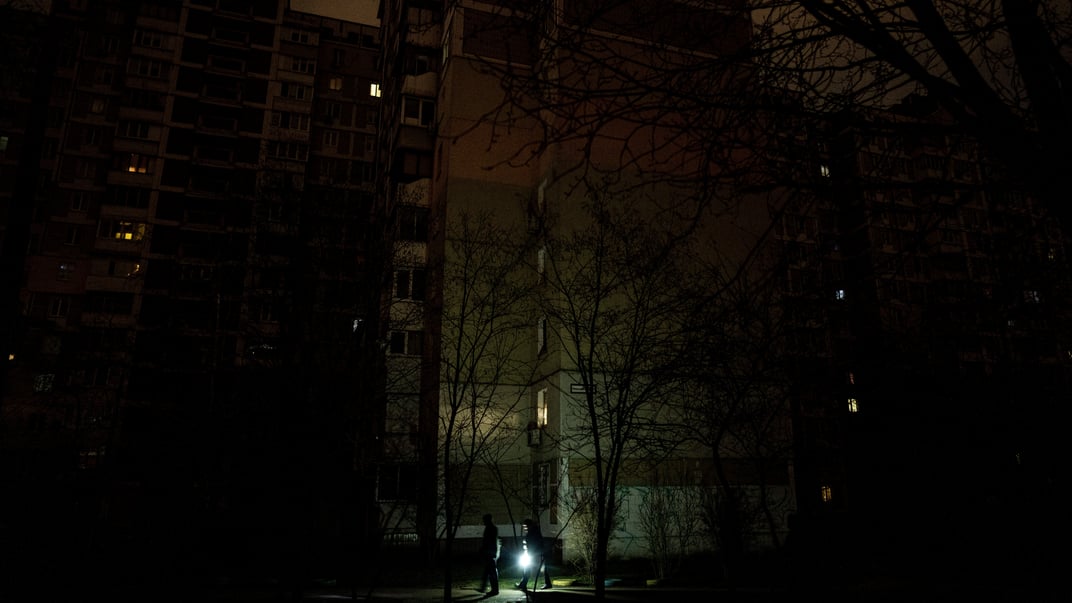 Иллюстративная фотография. Люди освещают дорогу фонариком при отключении электроэнергии в Киеве, 3 февраля 2023 года