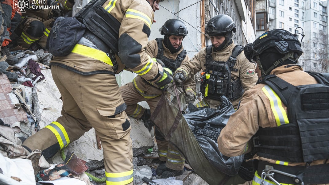 Рятувальники виносять тіло загиблої людини з-під завалів багатоповерхівки у Сумах