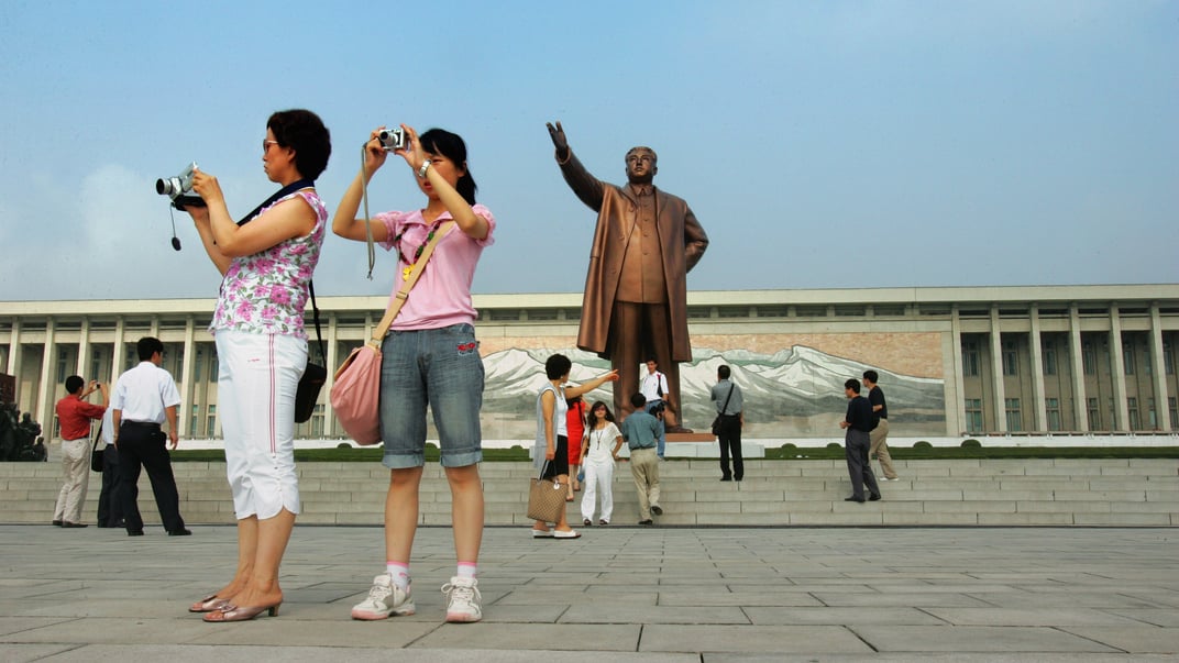 Китайські туристи роблять фото біля статуї покійного глави Північної Кореї Кім Ір Сена, встановленої на пагорбі Мансу в Пхеньяні, 5 серпня 2007 року