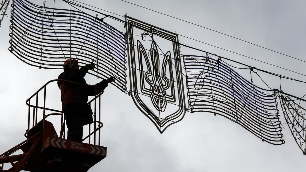 Сотрудник коммунальной службы ремонтирует свет на гербе Украины над улицей в центре Киева, Украина, 3 ноября 2017 года.