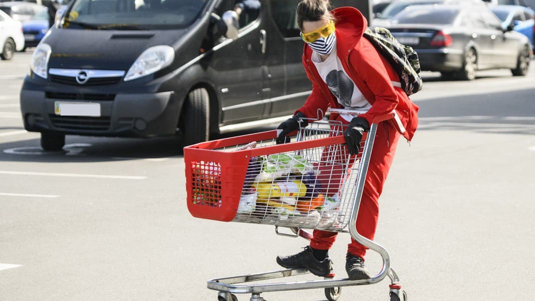 Дівчина в захисній масці з візком з покупками біля супермаркету у Києві, 31 березня 2020 року