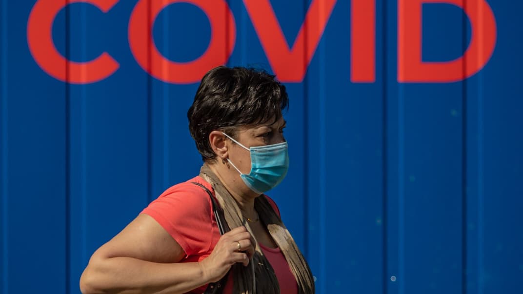 Женщина в защитной маске для лица проходит перед станцией тестирования на коронавирус в Праге, Чехия, 21 сентября 2020 года