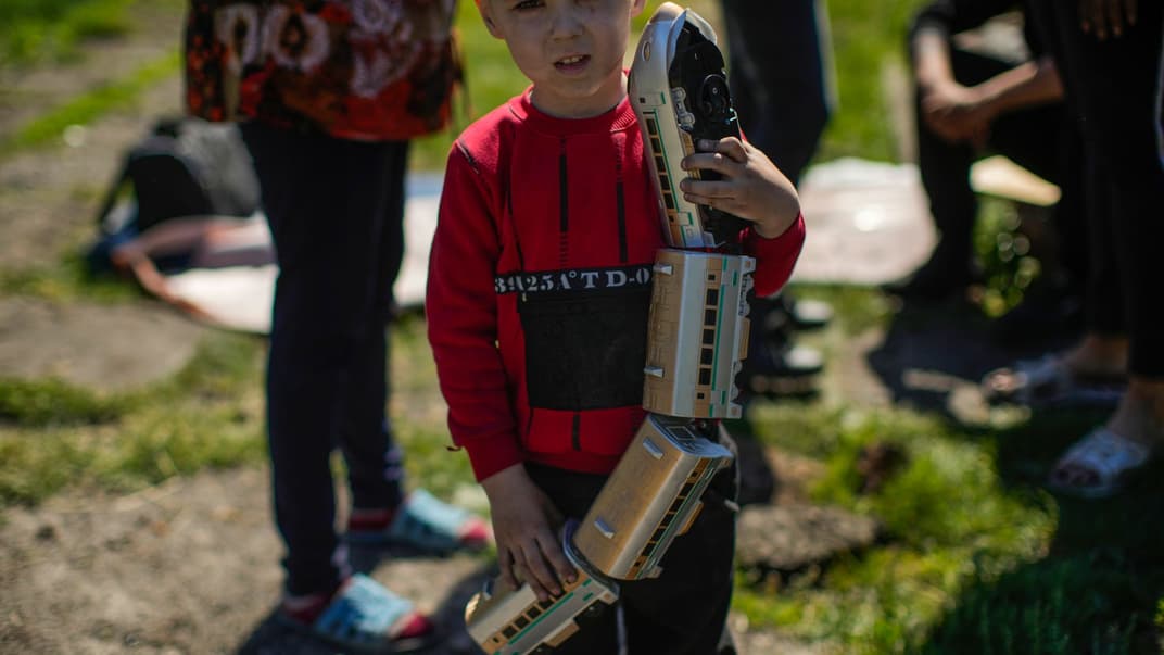 Дитина з іграшковим потягом біля сильно пошкодженого будинку своєї родини після російського удару по Покровську на Донеччині, 25 травня 2022 року