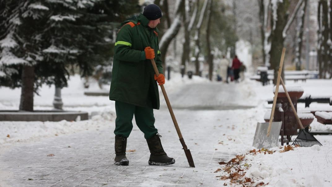 Співробітник комунальної служби чистить доріжку від снігу в Києві, 22 листопада 2023 року