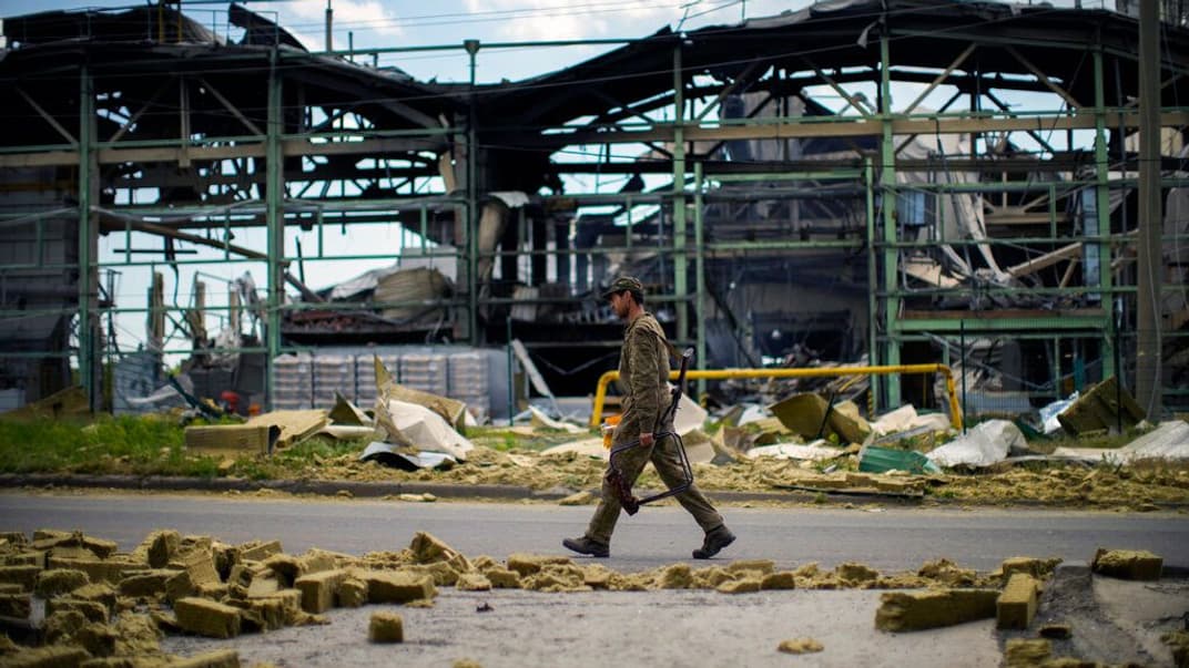 Украинский военный проходит мимо разрушенного здания в Бахмуте, 28 мая 2022 года