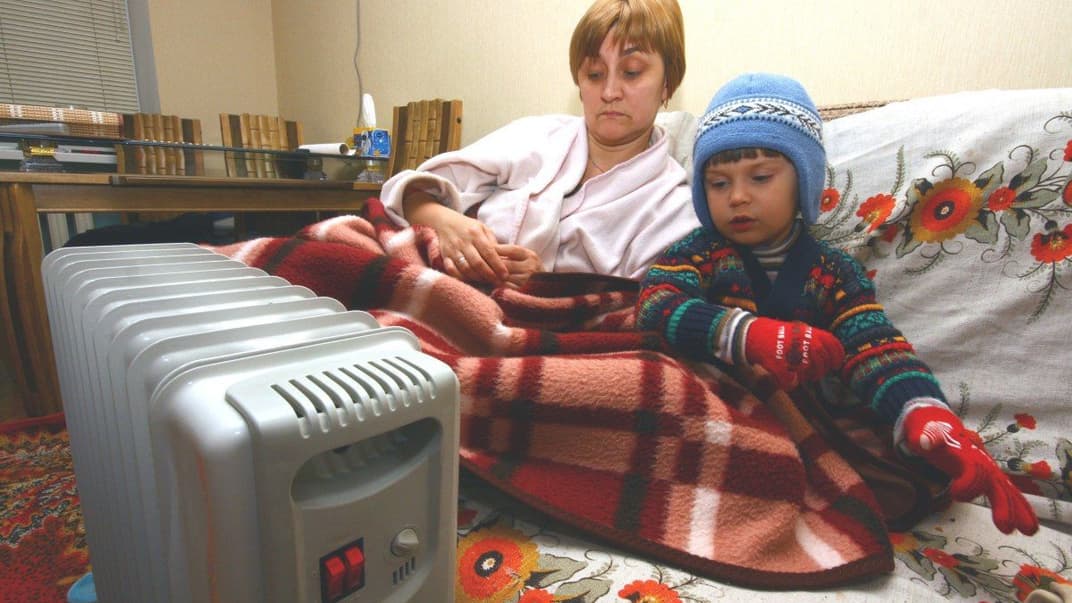 Мать и сын греются возле масляного электрического радиатора
