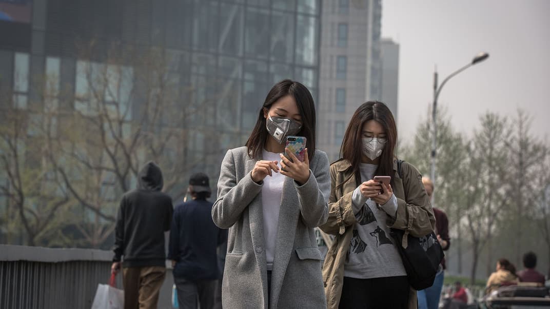 Женщины на улице в защитных масках в пиковые дни загрязнения воздуха в Пекине, Китай, 2 апреля 2018 года