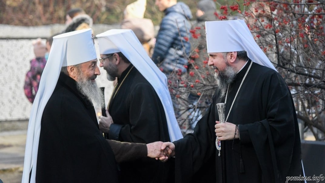 Предстоятели УПЦ МП и ПЦУ, митрополиты Онуфрий и Эпифаний, пожимают руку при встрече, за ними проходит предстоятель УГКЦ, митрополит Святослав