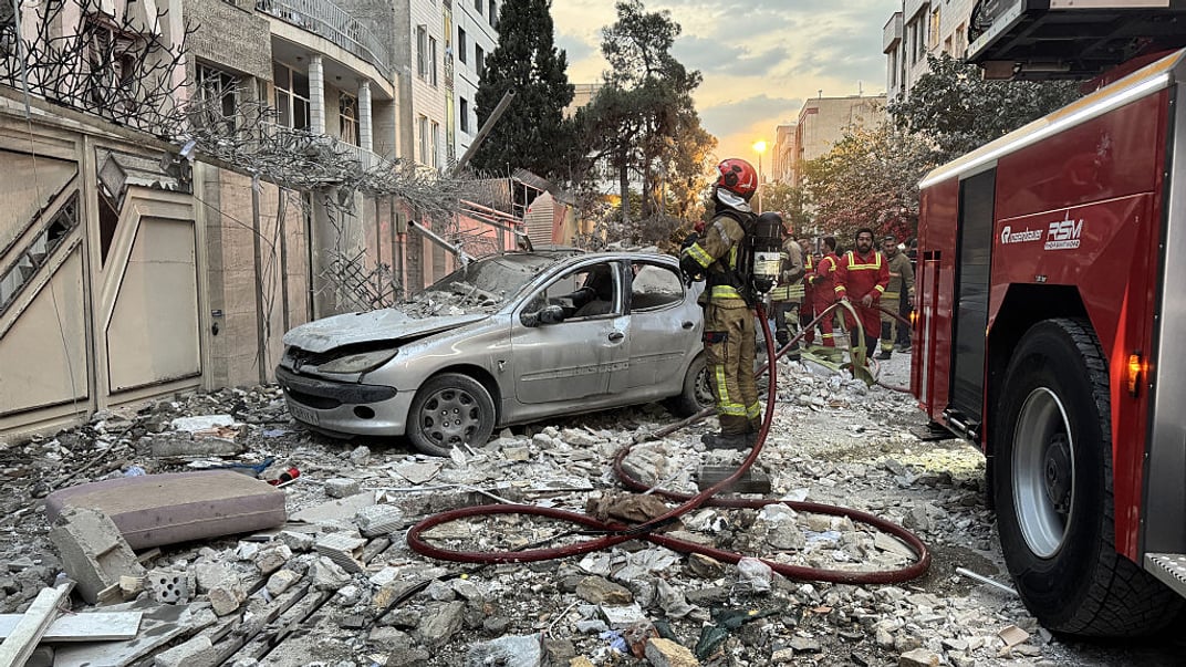 Служби швидкого реагування збираються біля будівлі, яка постраждала від ізраїльського удару в Тегерані 13 червня 2025 року