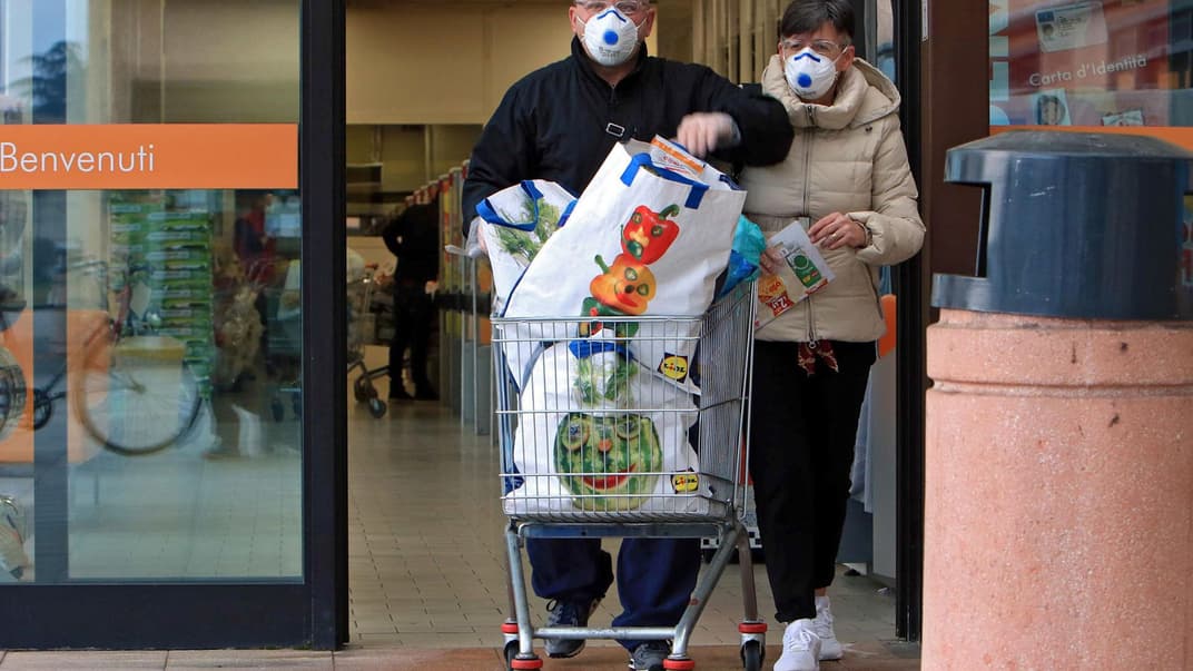 Люди в защитных масках выходят с покупками из супермаркета в Казальпустерленго в регионе Ломбардия — одном из северных итальянских городов, которые были закрыты на карантин из-за вспышки коронавируса в Италии, 23 февраля 2020 года