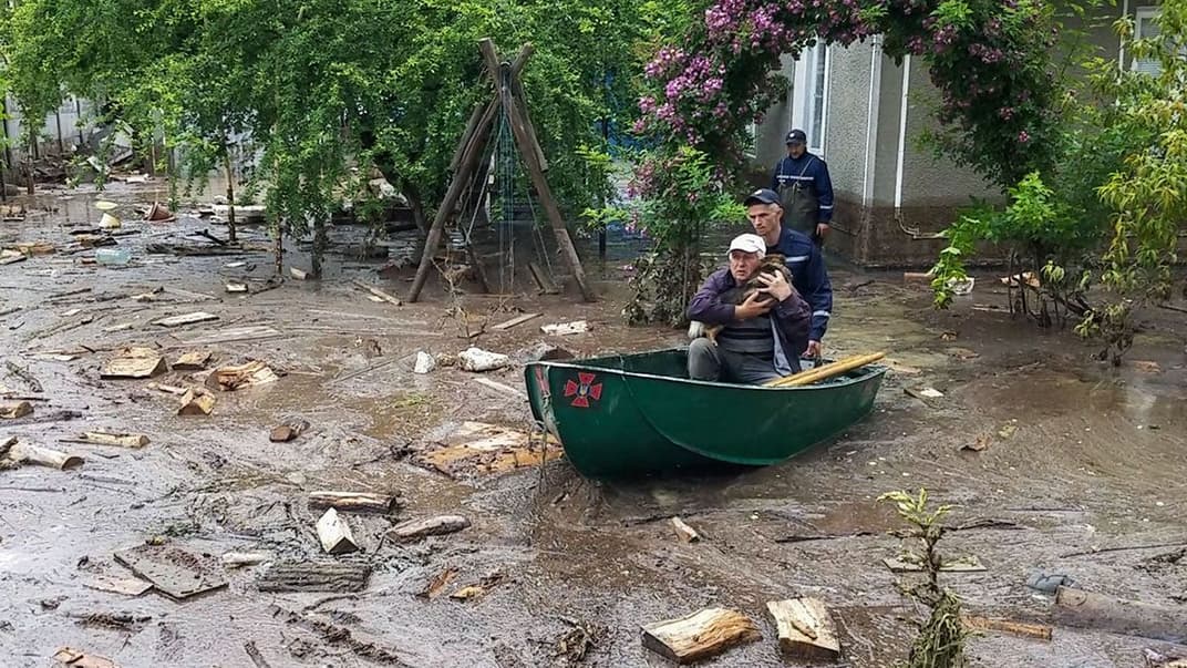 Спасатели вывозят человека с собакой из его затопленного двора в селе Черновицкой области, 25 июня 2020 года