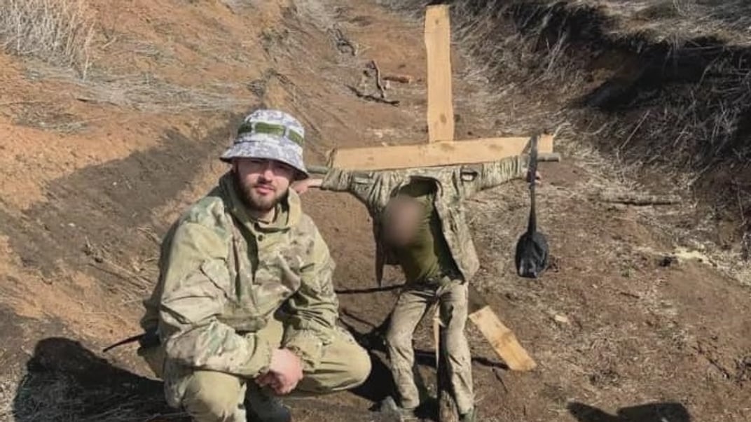 Владислав Пастух фотографируется на фоне привязанного к кресту военнослужащего