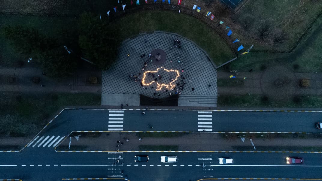 Люди зажгли свечи, разместив их в форме карты Украины, во время памятного мероприятия к годовщине освобождения Бучи, 31 марта 2023 года