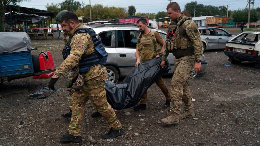 Украинские военнослужащие несут мешок с телом человека после обстрела рф в Запорожье, 30 сентября 2022 года