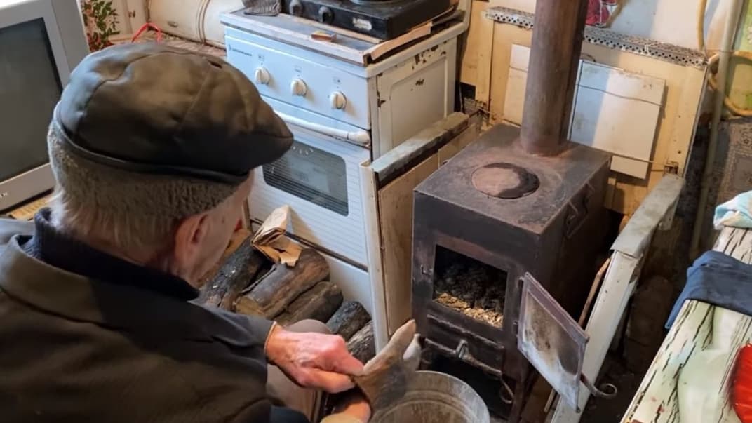 Микола, житель прифронтовій Мар'їнки, опалює свій будинок «буржуйкою»