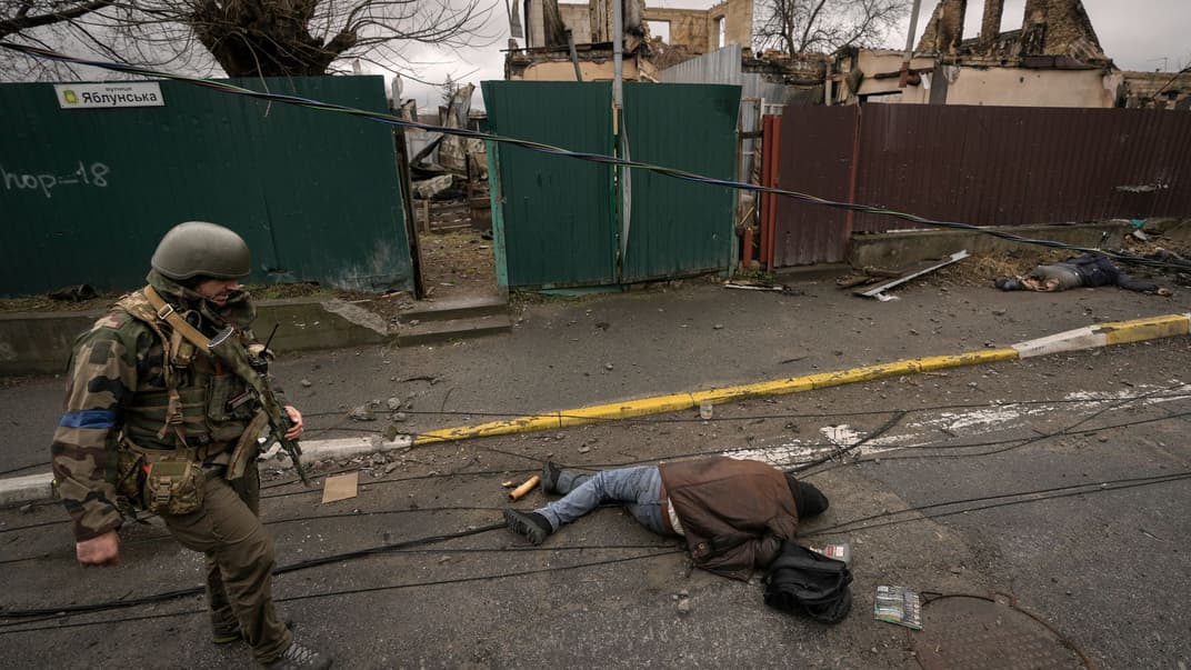 Український військовослужбовець біля тіла вбитого росіянами мирного жителя в Бучі, 2 квітня 2022 року