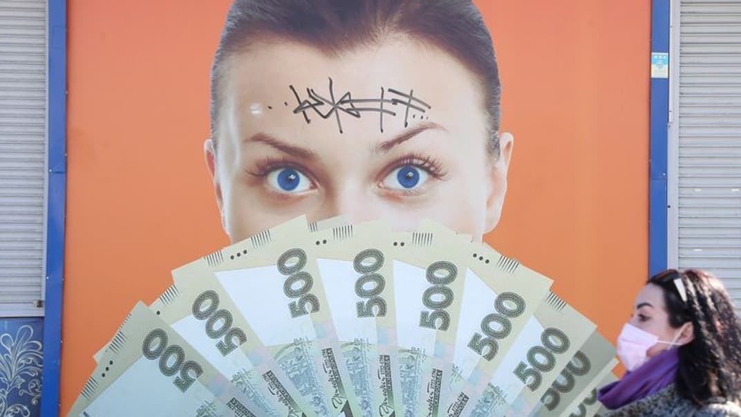 Дівчина в медичній масці проходить біля рекламного плаката під час карантину в Києві