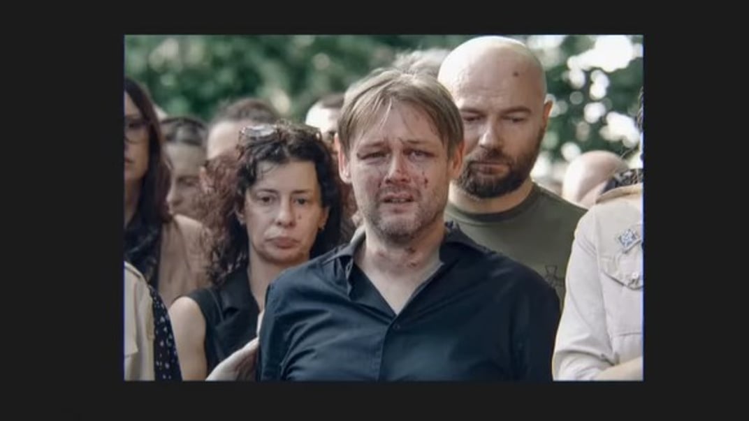Кадр из рекламы «Медузы», на котором изображен Ярослав Базилевич во время похорон своих трех дочерей, погибших от российского удара