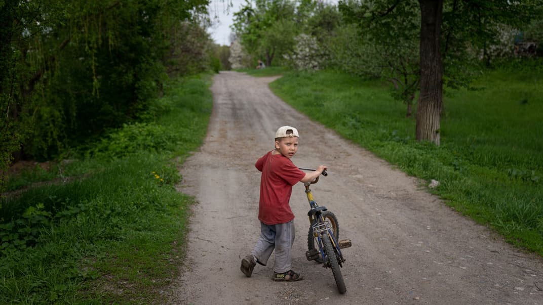 Хлопчик гуляє з велосипедом в селі Семенівка Донецької області, 28 квітня 2022 року