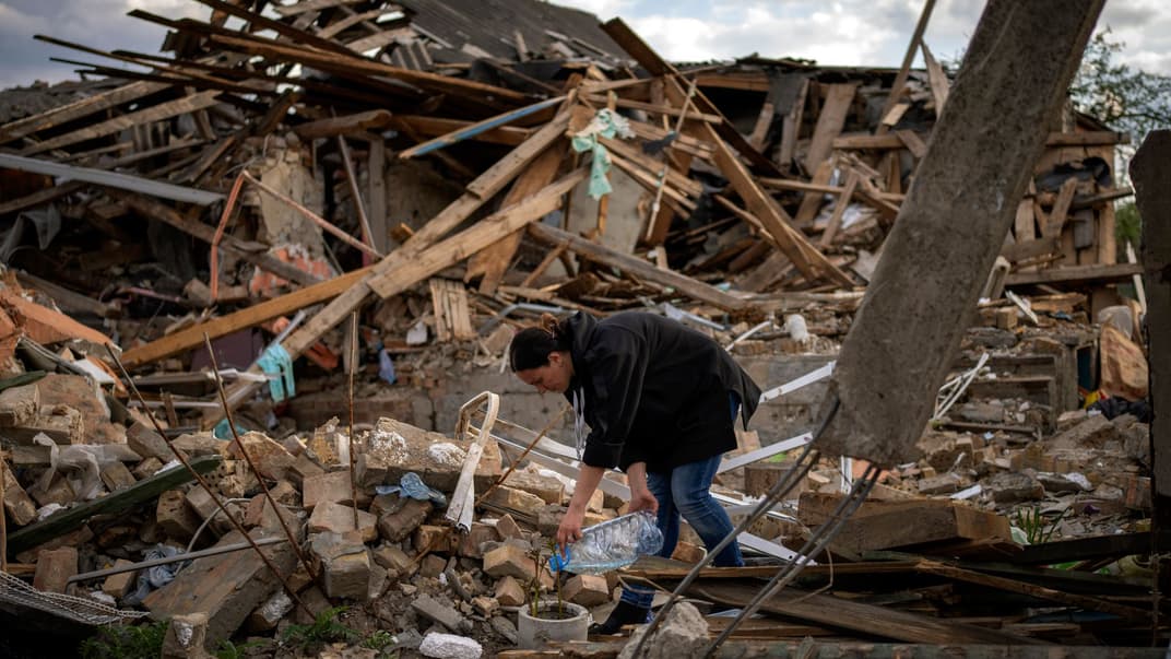Жінка поливає кілька квітів, які вціліли в саду її будинку в Ірпені під Києвом, 3 травня 2022 року