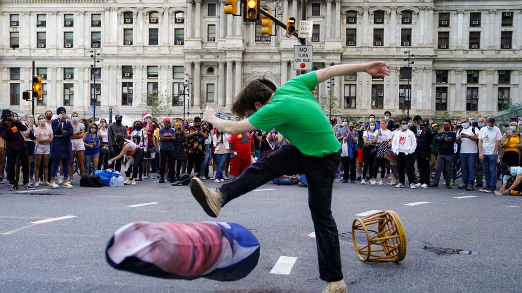 Мужчина бьет ногой чучело Дональда Трампа после того, как американские медиа спрогнозировали победу Джо Байдена на выборах президента США, Филадельфия, Пенсильвания, 7 ноября 2020 года