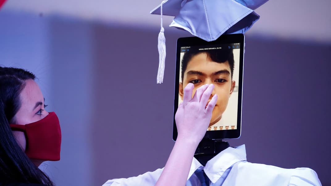 Учителька поправляє зображення учня на планшеті під час імпровізованої церемоніі випуску учнів у школі в місті Тагіг, Філіппіни, 22 травня 2020 року