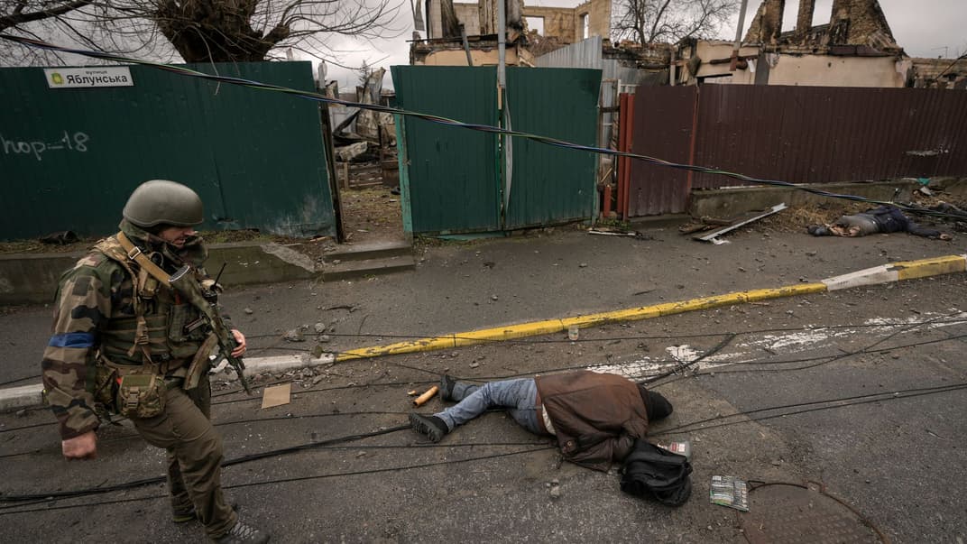 Український військовослужбовець біля тіла вбитого росіянами мирного жителя у Бучі, 2 квітня 2022 року