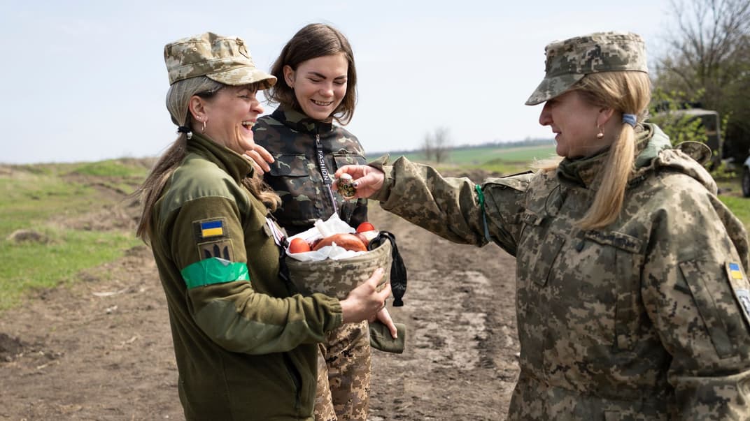 Українські військові усміхаються, несучи кошик із паскою та писанками під час святкування Великодня під Запоріжжям, 24 квітня 2022 року