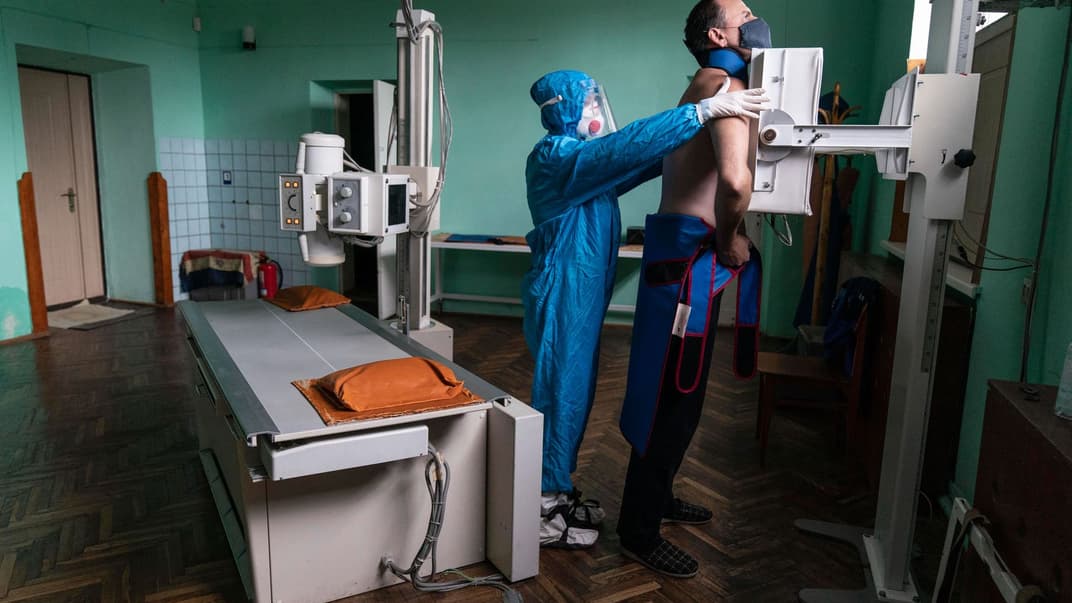 Медик, одягнений у спеціальний костюм для захисту від коронавірусу, готує пацієнта з коронавірусом до рентгенографії легенів у міській лікарні в Стрию, Україна, вівторок, 29 вересня 2020 року.