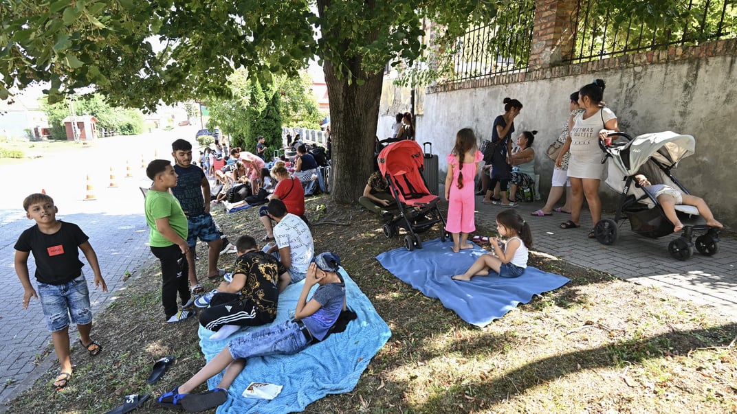 Українські біженці із Закарпаття сидять на тротуарі біля притулку в угорському селі Коч, звідки їх виселили Українські біженці із Закарпаття сидять на тротуарі біля притулку в угорському селі Коч, звідки їх виселили