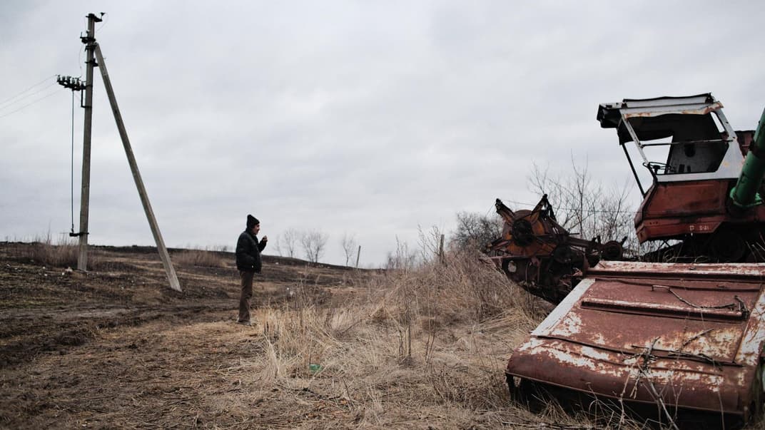 Володимир Олексійович, мешканець села Новоолександрівка Луганської області, дивиться на рештки сільськогосподарської техніки, кинуті на околиці села. Новоолександрівка розташована поблизу лінії розмежування, і нині в селі живуть лише десять осіб