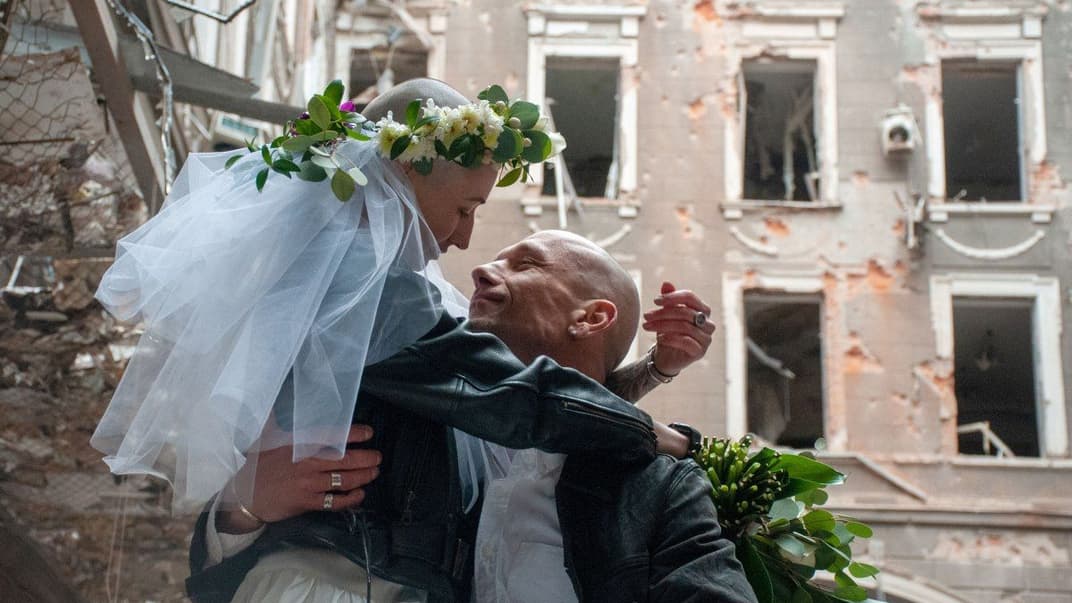 Волонтери Настя та Антон у день свого весілля фотографуються на фоні зруйнованих будинків, у Харкові, 3 квітня 2022 року
