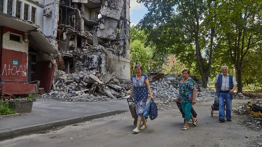 Жители Северной Салтовки идут мимо разрушенного дома