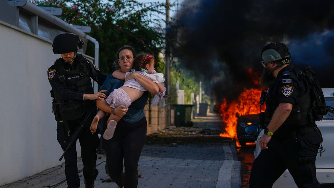 Иллюстративное фото. Полицейские эвакуируют женщину и ребенка с места, в которое попала ракета палестинских боевиков, в городе Ашкелоне на юге Израиля, 7 октября 2023 года