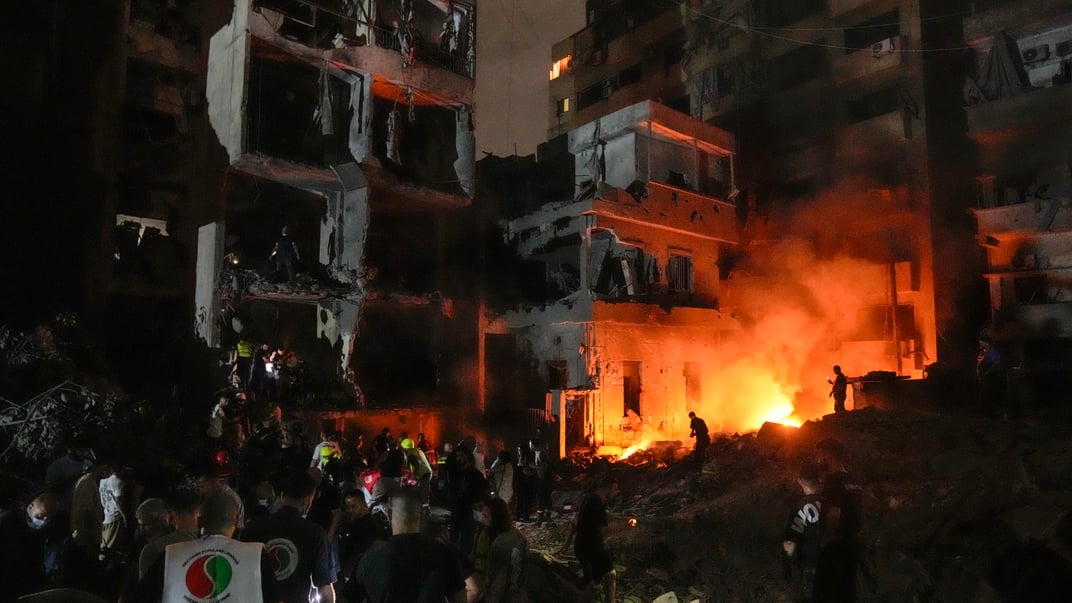 Люди збираються перед зруйнованими будівлями, які постраждали внаслідок ізраїльського авіаудару в центрі Бейрута, Ліван, четвер, 10 жовтня 2024 року